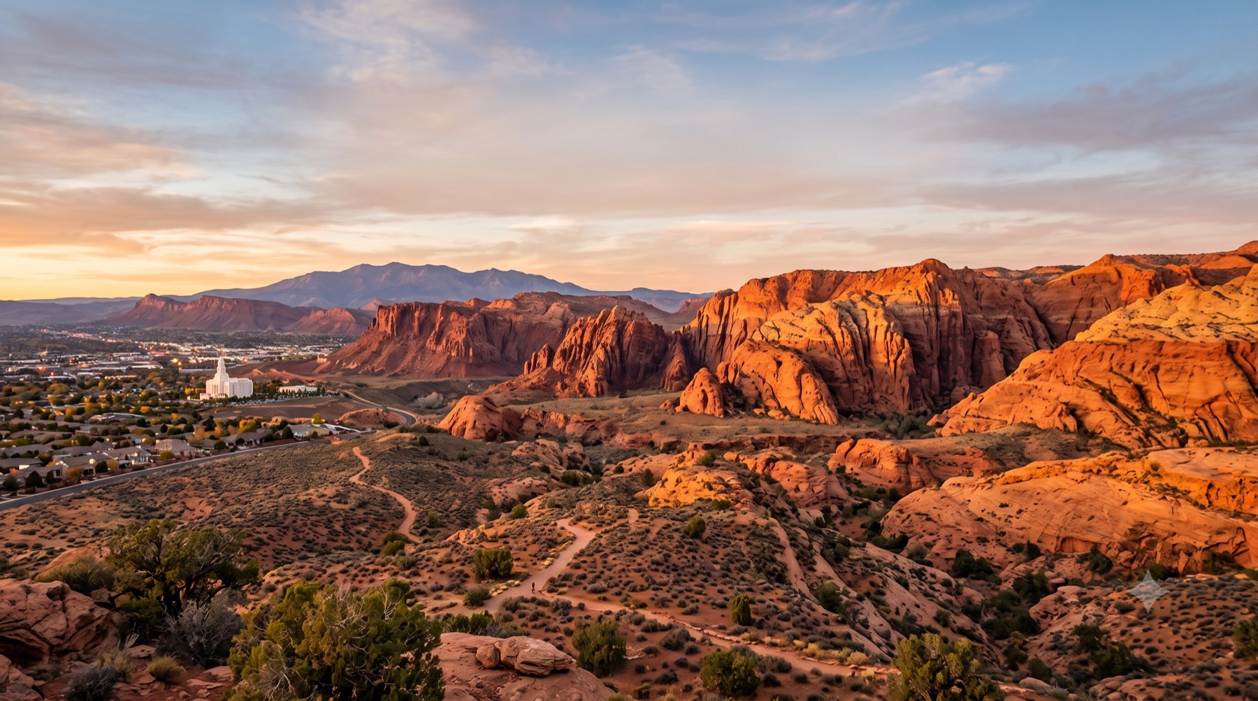 Red sandstone cliffs above St. George, Utah at sunset, with the city and temple in the valley below